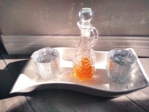 Glass decanter with facial serum in white tray with glass candle holders