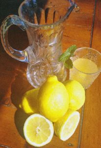 lemons, glass pitcher and glass of lemonade 